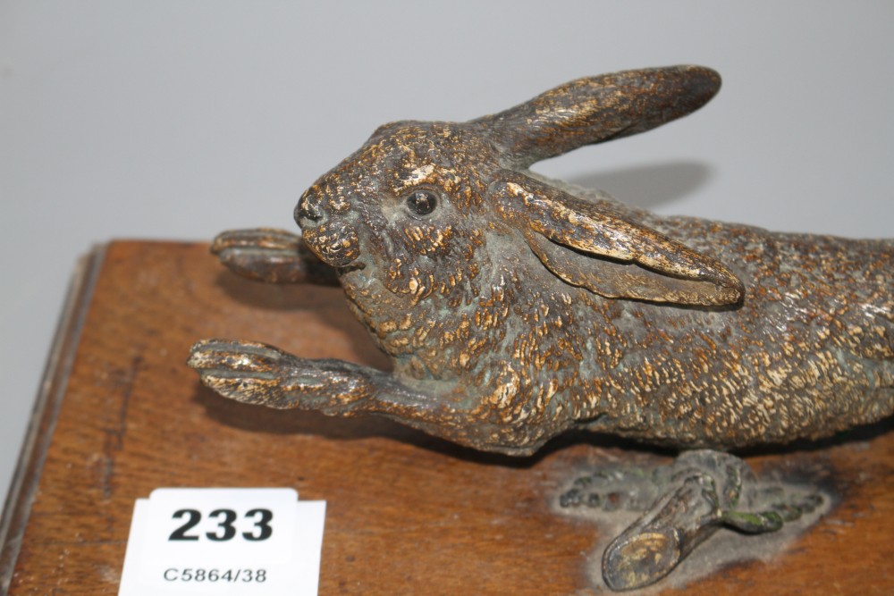 An Austrian cold painted door knocker modelled as a running hare, with oak mount, overall length 30cm, width 14cm, length of hare 25cm